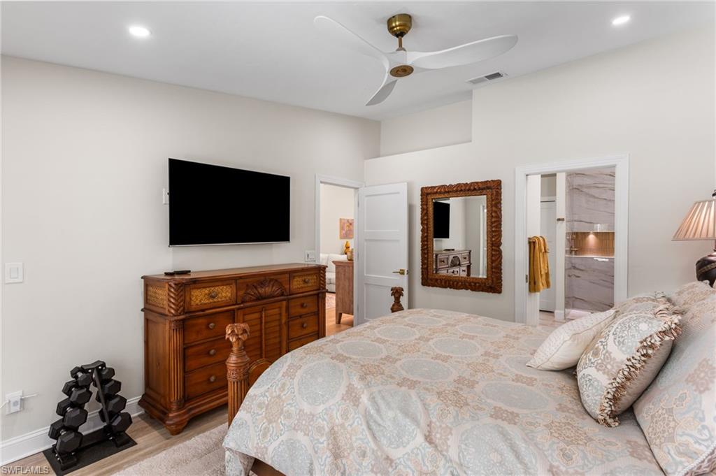 754 Wiggins Bay Drive Naples, FL 34110 - Photo 14 of 34 a bedroom with a bed and a flat tv screen on dresser