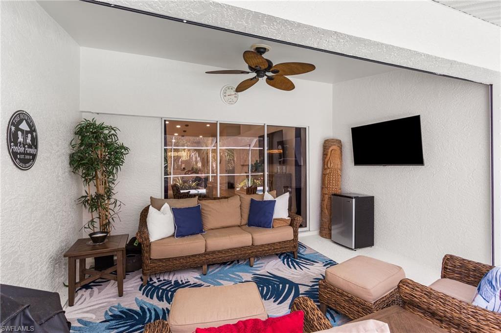 754 Wiggins Bay Drive Naples, FL 34110 - Photo 23 of 34 a living room with furniture a flat screen tv and a floor to ceiling window
