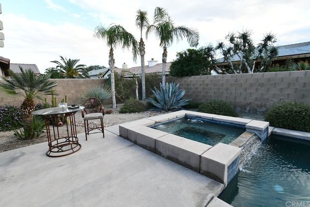 a view of a swimming pool with chairs and table in patio