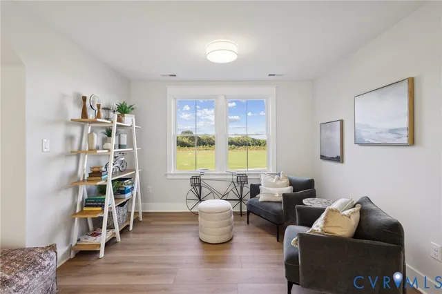 a living room with furniture and a bookshelf with wooden floor