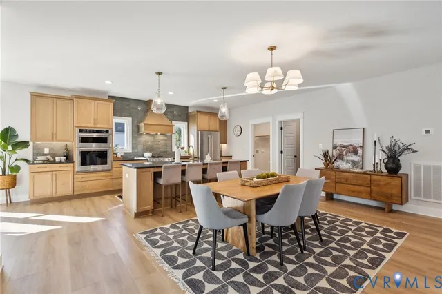 a dining room with wooden floor a chandelier a wooden table and chairs