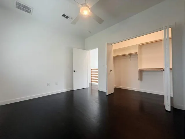 an empty room with a ceiling fan and windows