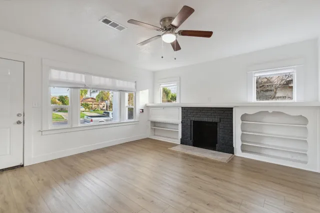 an empty room with windows and a ceiling fan