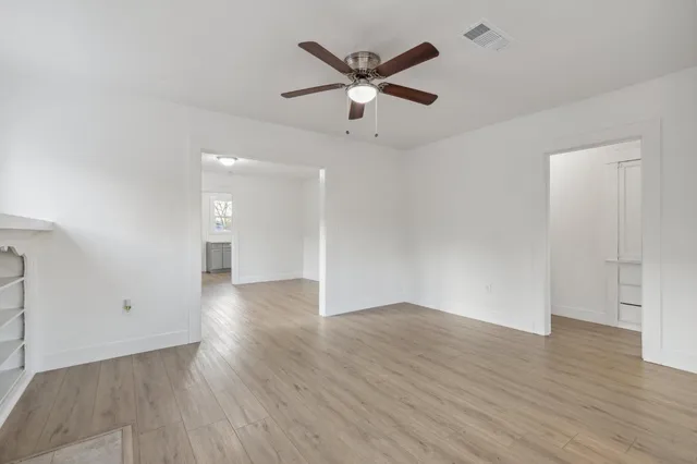 an empty room with wooden floor and ceiling fan