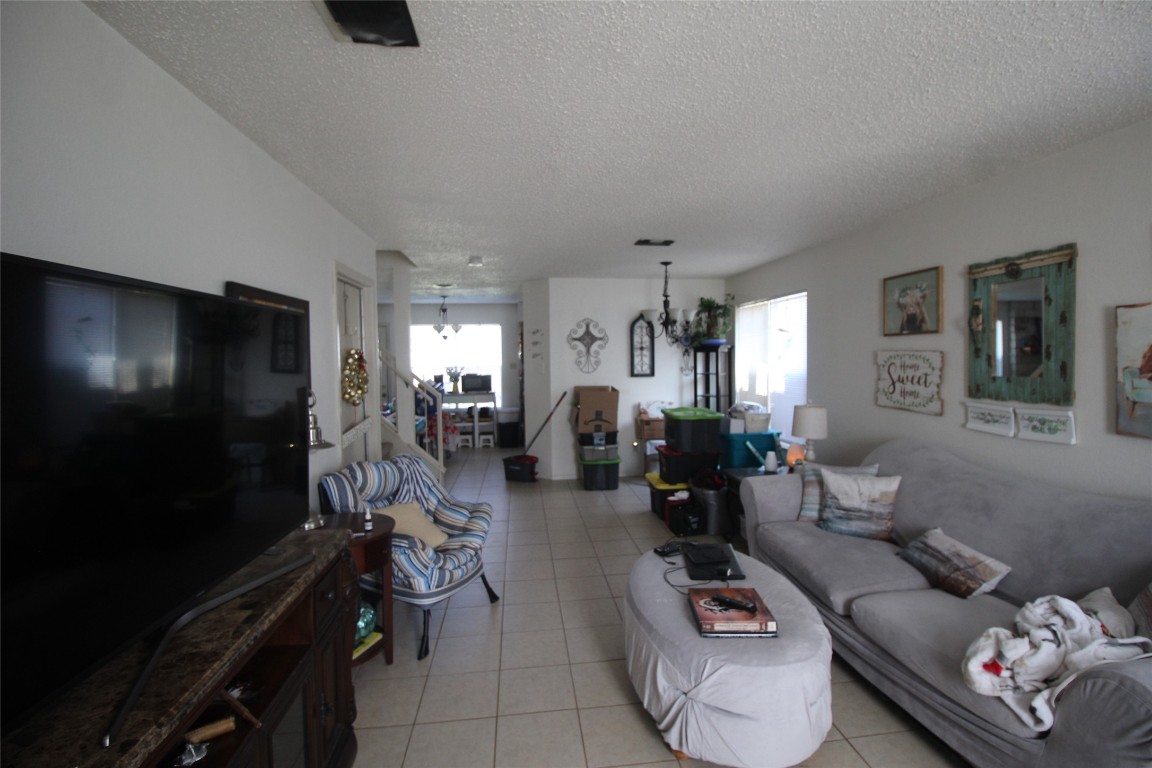 808 Angleton Cove Austin, TX 78748 - Photo 4 of 17 Living area with a textured ceiling, light tile patterned floors, and a chandelier