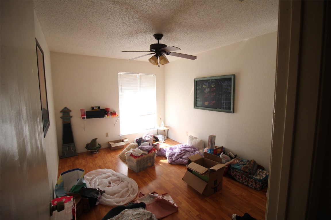 808 Angleton Cove Austin, TX 78748 - Photo 10 of 17 Bedroom with a textured ceiling, wood finished floors, and ceiling fan
