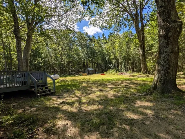 a view of a house with a big yard and large trees