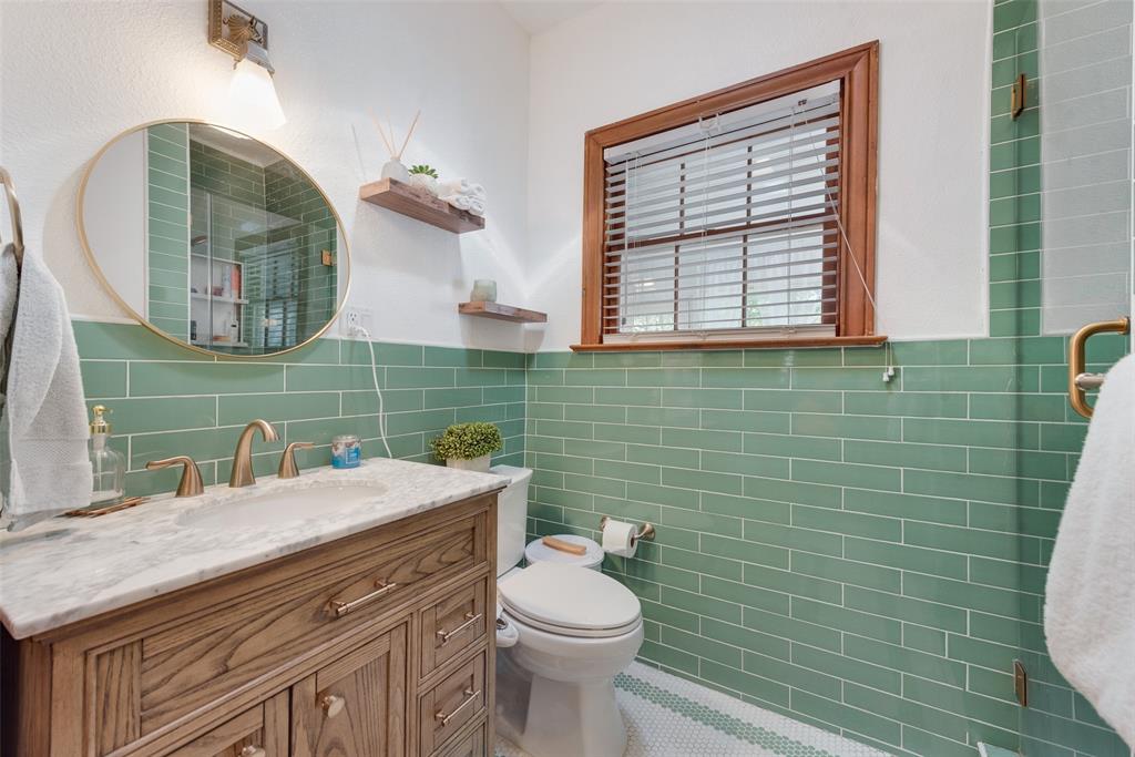 233 East High Street Wills Point, TX 75169 - Photo 22 of 40 Full bath featuring vanity, tile walls, tiled shower, wainscoting, and tile patterned floors