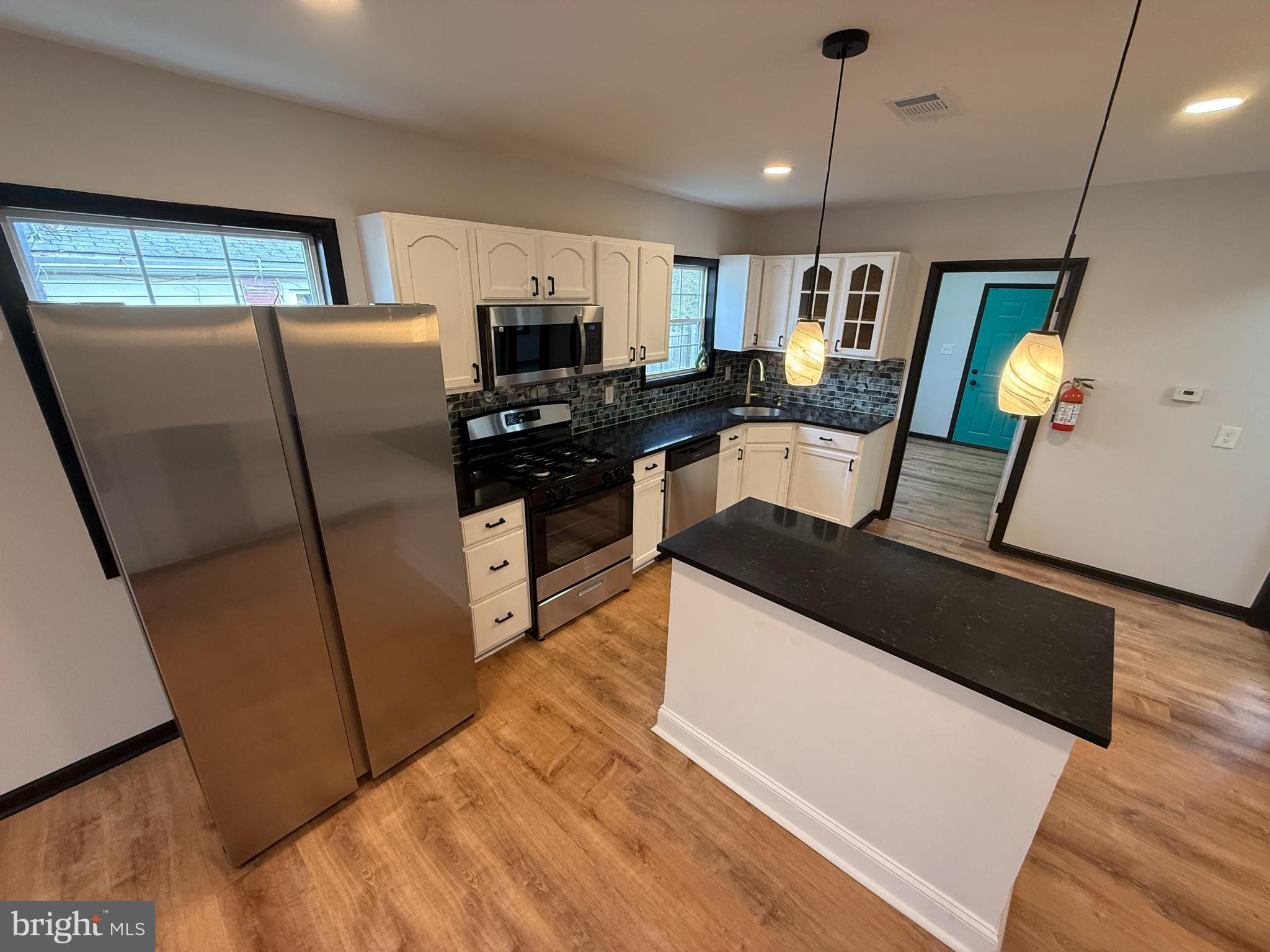 11 Sunset Lane Bridgeton, NJ 08302 - Photo 6 of 16 a kitchen with stainless steel appliances granite countertop a refrigerator a sink dishwasher a stove and a dining table with wooden floor