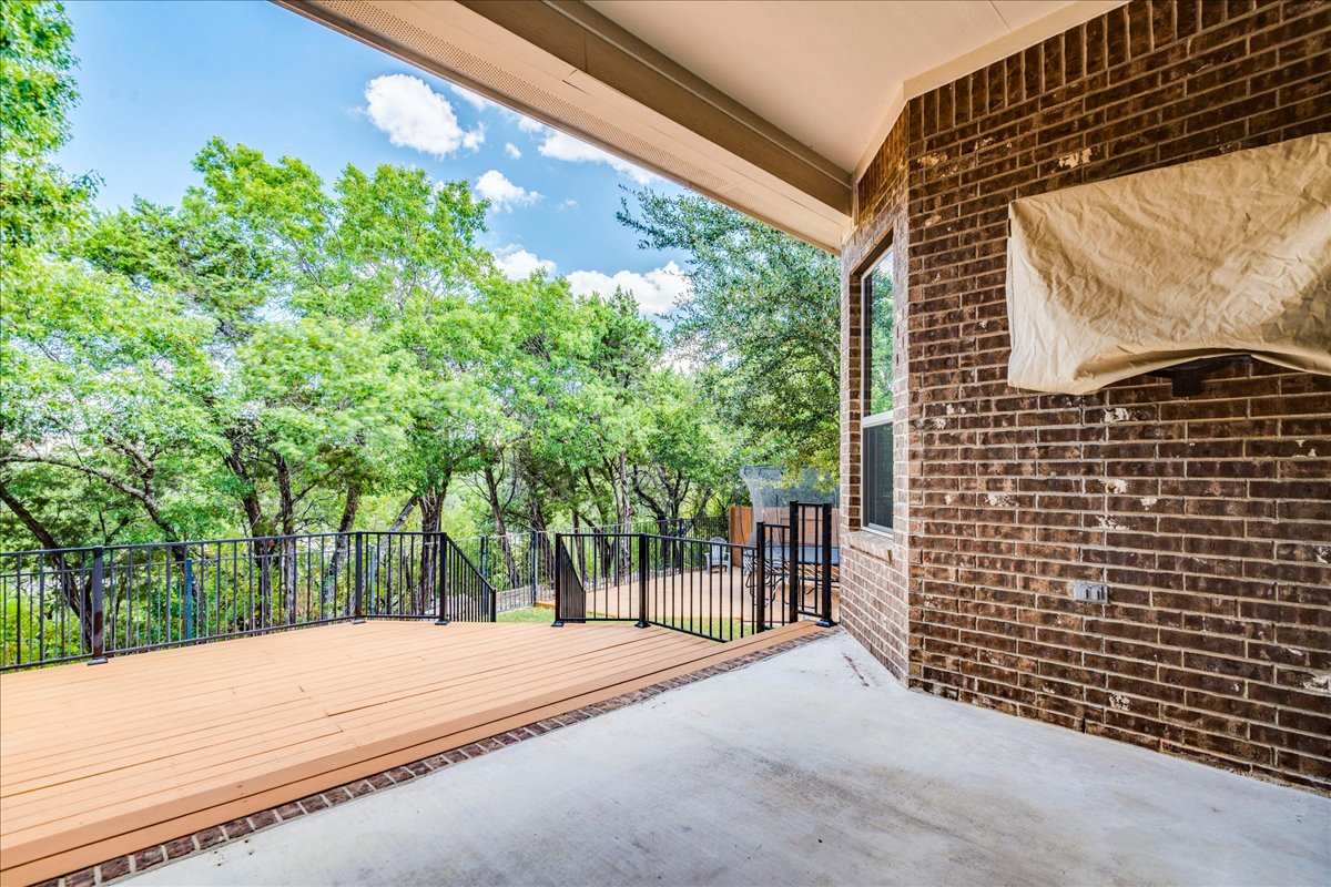 5009 Inks Clearing Lane Austin, TX 78738 - Photo 6 of 34 A spacious covered patio transitions seamlessly to an elevated deck overlooking a scenic wooded backdrop.