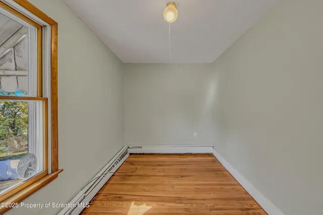 a view of a room with wooden floor and small window