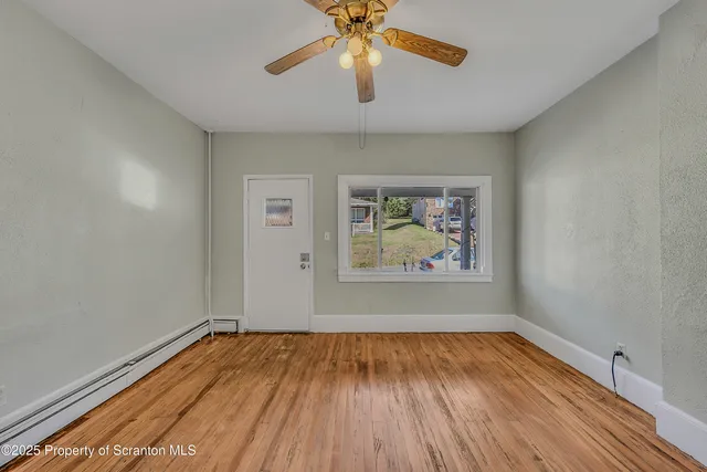a view of room with window ceiling fan and wooden floor