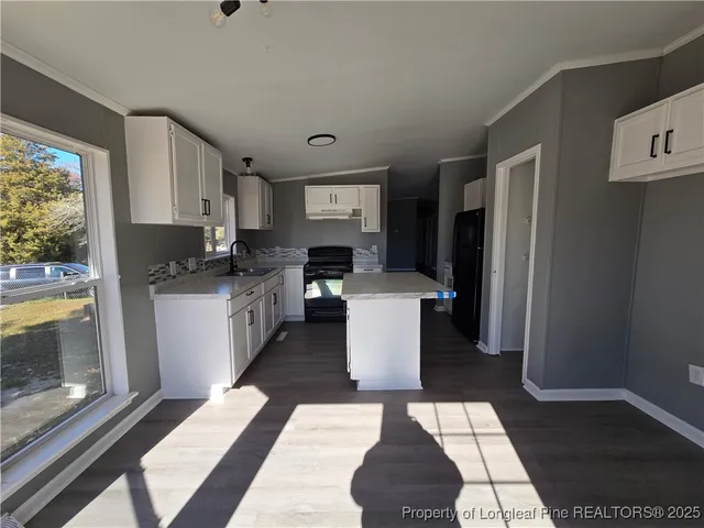 a kitchen with stainless steel appliances a sink a stove a refrigerator cabinets and a dining table