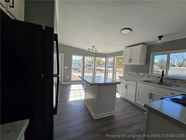 a kitchen with granite countertop a refrigerator a sink dishwasher a stove and a dining table with wooden floor