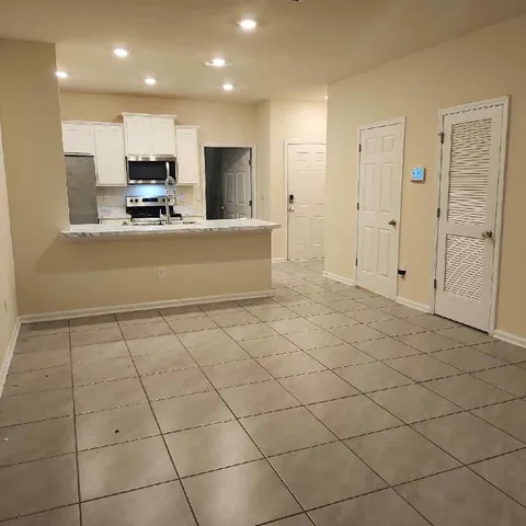 a view of kitchen with stainless steel appliances cabinets and living room view