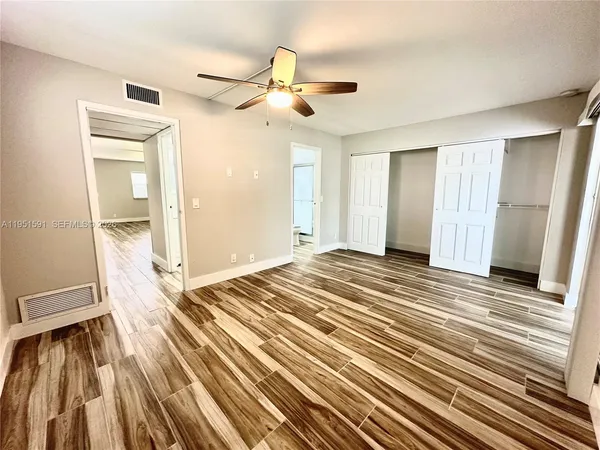 a view of a room with wooden floor and ceiling fan