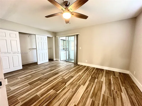 a view of empty room with wooden floor and fan