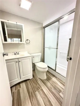 a bathroom with a sink a toilet a mirror and shower