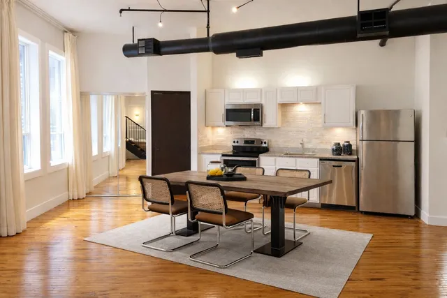 a kitchen with stainless steel appliances wooden floor dining table and chairs