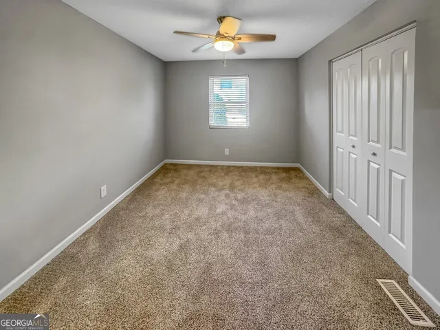 an empty room with windows and fan