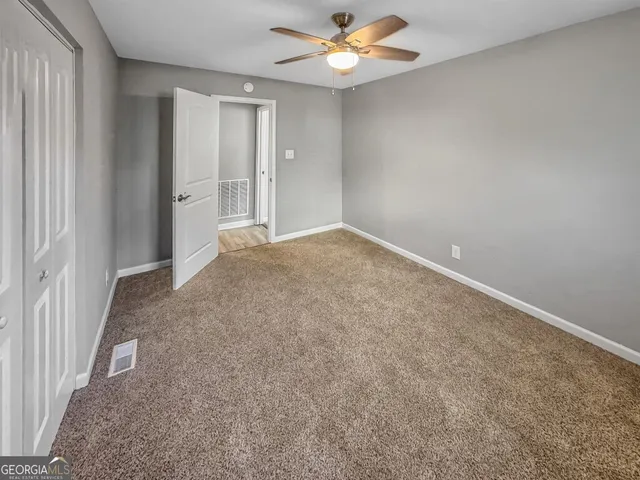 an empty room with closet and a chandelier fan