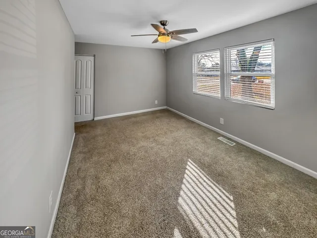 an empty room with windows and ceiling fan