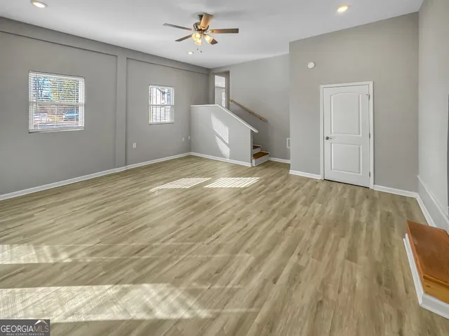a view of an empty room with window and wooden floor