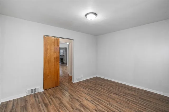 a view of an empty room with wooden floor and closet