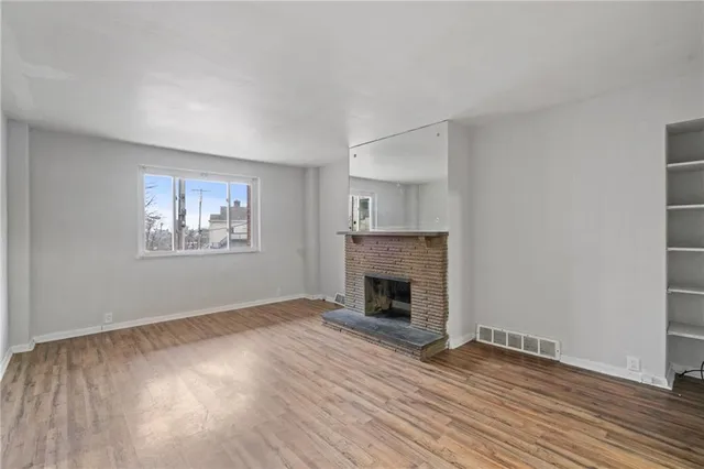 a view of empty room with wooden floor and fireplace