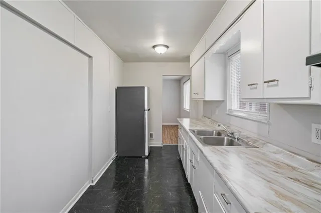 a kitchen with stainless steel appliances granite countertop a refrigerator a sink and white cabinets