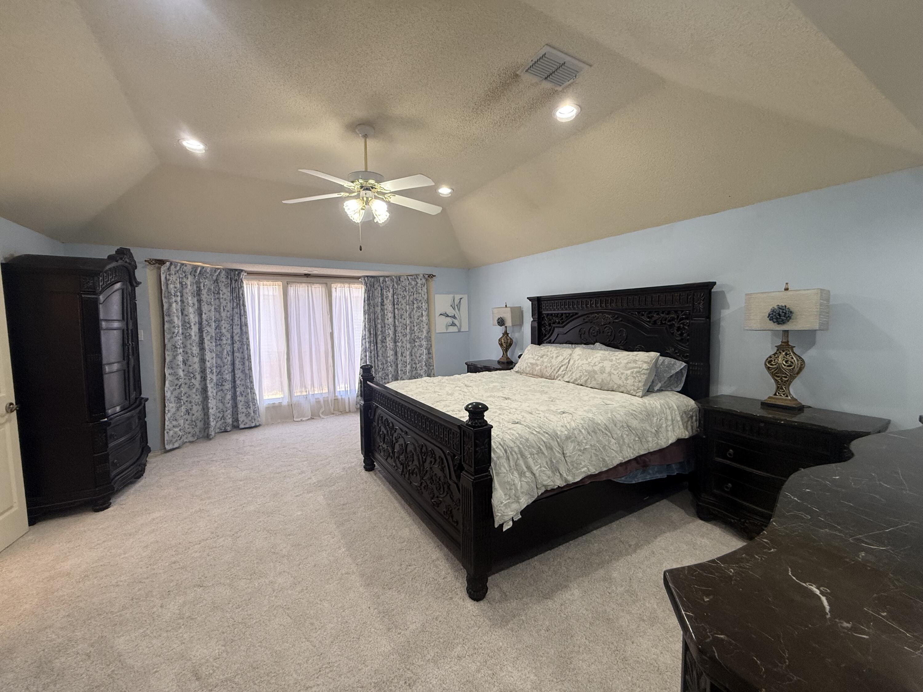 4810 99th Street Lubbock, TX 79424 - Photo 23 of 48 a spacious bedroom with a bed and a chandelier