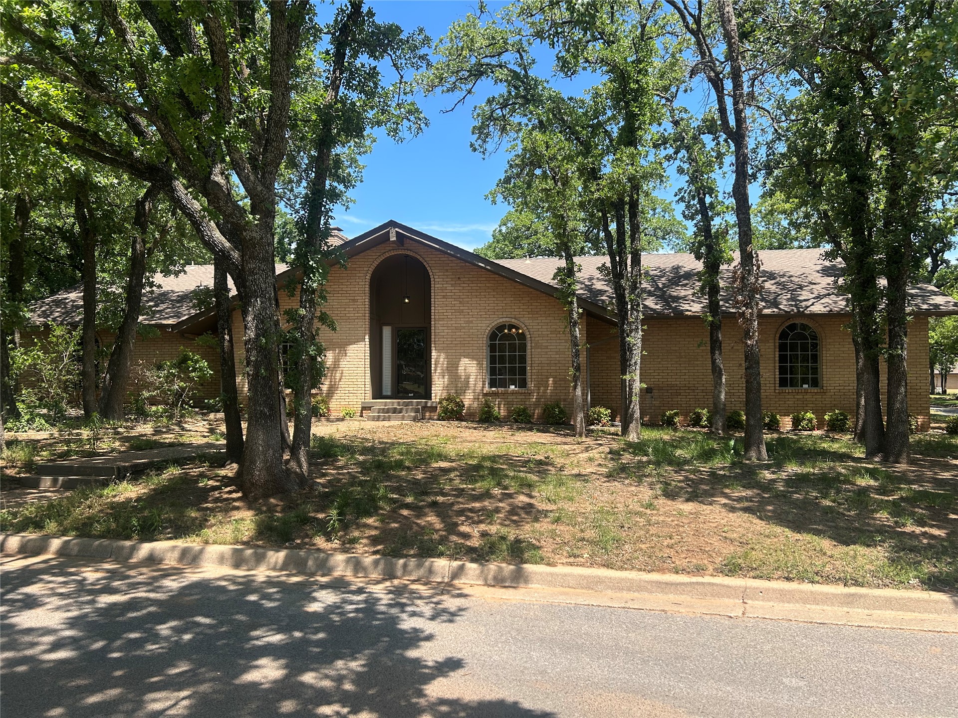 2913 Springdale Lane Duncan, OK 73533 - Photo 1 of 32 Brick exterior with an arched entry, two arched windows, a pitched roofline, and mature trees surrounding the property