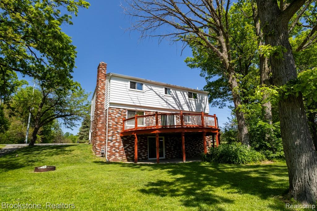 30100 Armada Ridge Road Richmond, MI 48062 - Photo 4 of 29 Rear exterior featuring a spacious elevated deck with wood railing, brick chimney, white siding, and a walkout lower level
