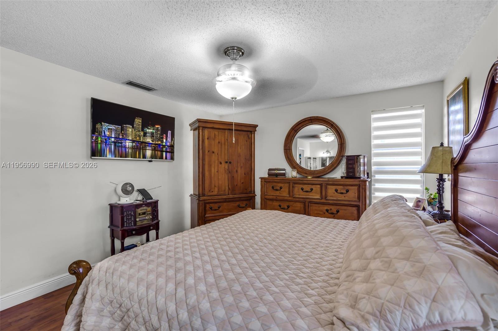 9466 Southwest 6th Lane Miami, FL 33174 - Photo 15 of 34 a bedroom with a bed a mirror and a table with wooden floor