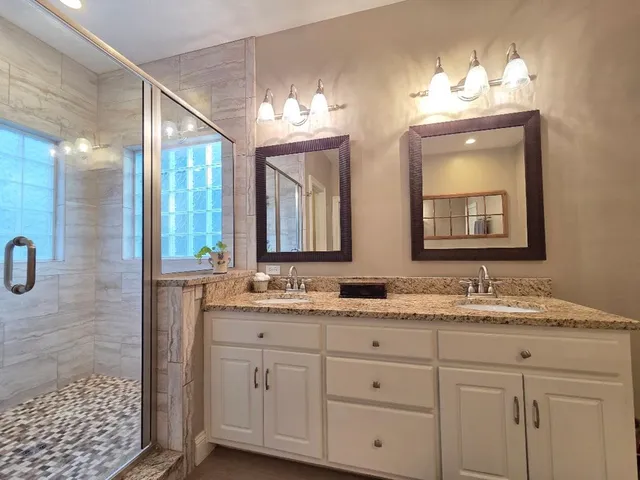 a bathroom with a granite countertop sink a mirror and shower