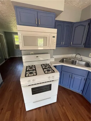 a white stove top oven sitting inside of a kitchen with granite countertop wooden cabinets