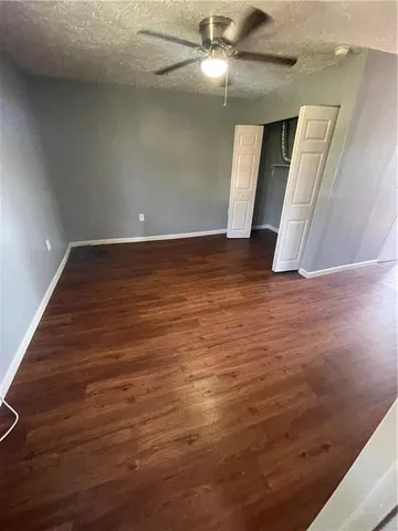 en empty room with wooden floor and ceiling fan