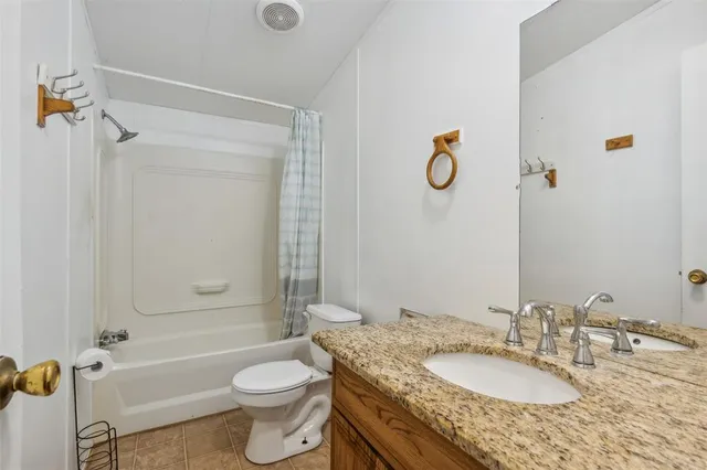 a bathroom with a granite countertop toilet a sink and a bathtub
