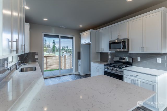 a kitchen with stainless steel appliances granite countertop a stove a sink a refrigerator and a sink