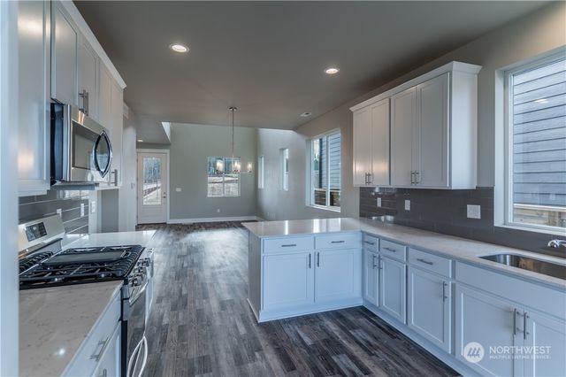 a large kitchen with stainless steel appliances granite countertop a lot of counter space and wooden floors