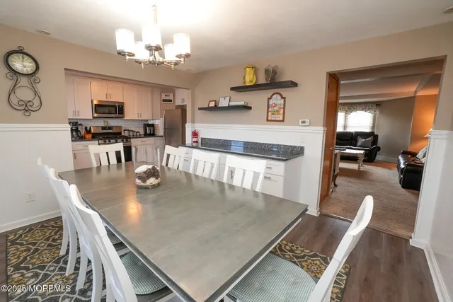 a kitchen with stainless steel appliances granite countertop a stove top oven a sink dishwasher and white cabinets with wooden floor