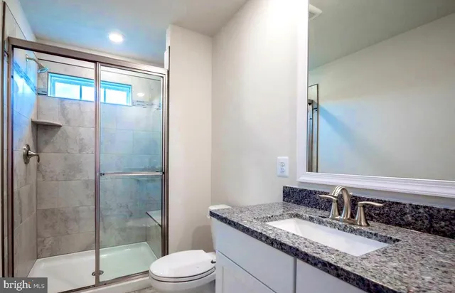a bathroom with a granite countertop sink toilet and shower