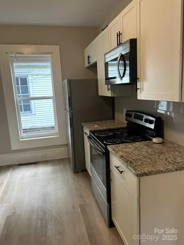 a kitchen with stainless steel appliances granite countertop a stove a sink and a microwave