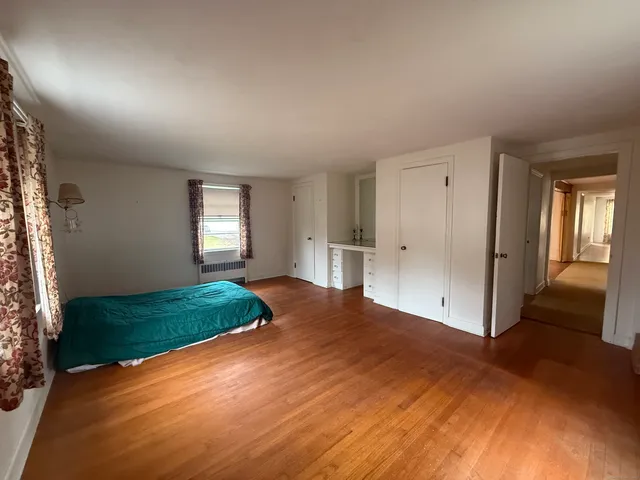 a view of empty room with wooden floor and window