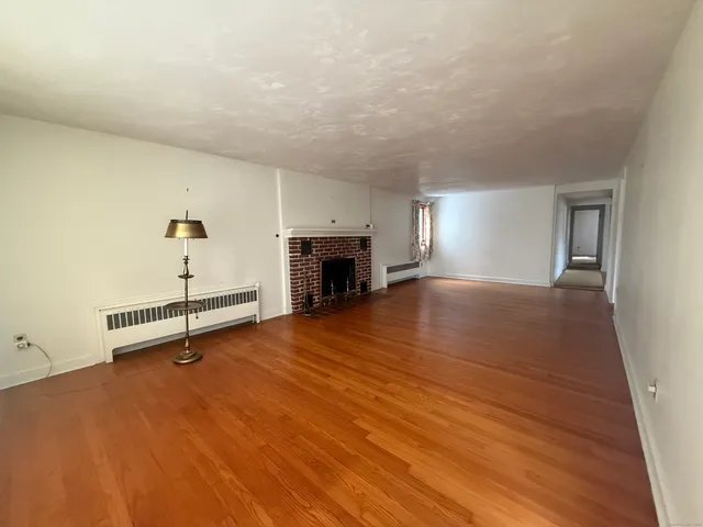 an empty room with wooden floor and fireplace