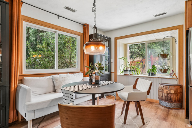Wood-finish flooring, a contemporary pendant light fixture, and two large windows with natural wood trim