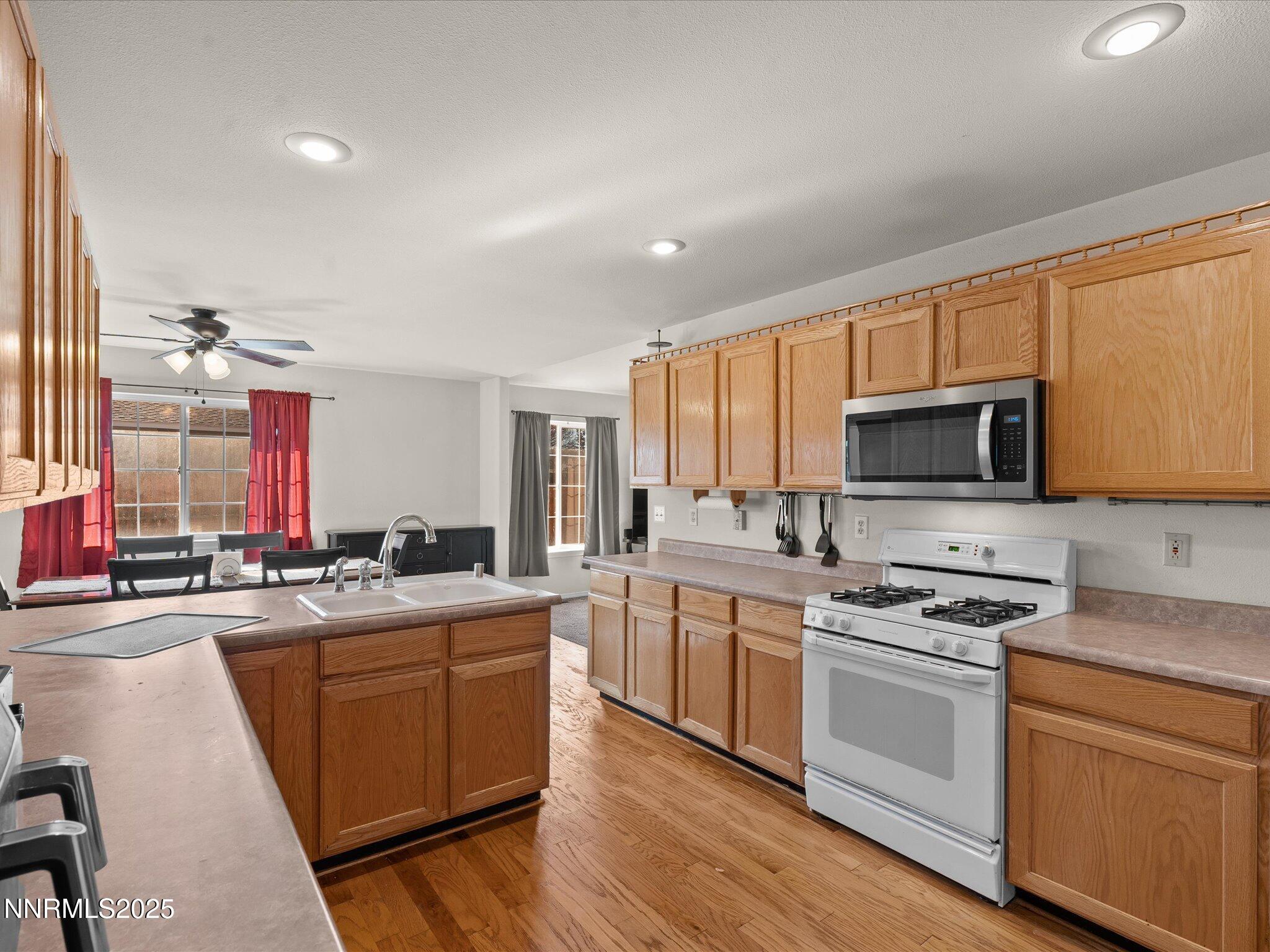 1819 Bogie Court Fernley, NV 89408 - Photo 16 of 46 a kitchen with stainless steel appliances kitchen island granite countertop a sink stove cabinets and wooden floor