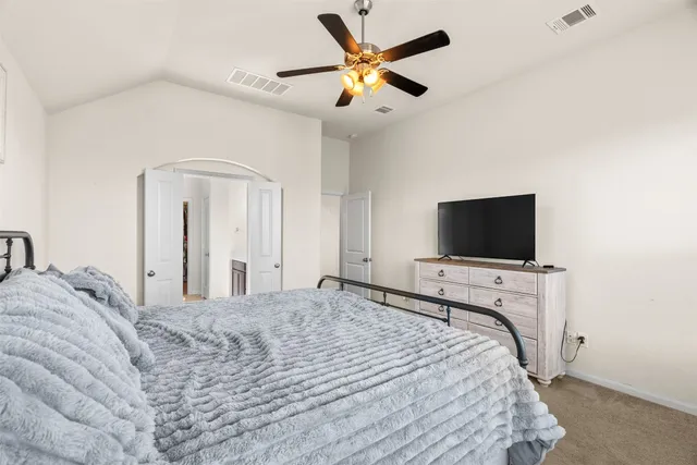 a bedroom with a bed and a flat tv screen on dresser