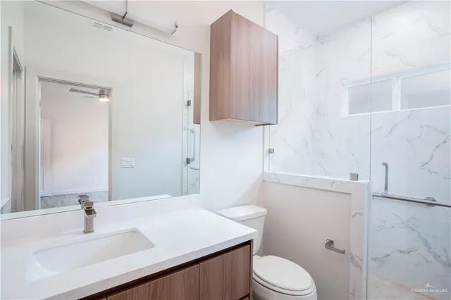 a bathroom with a sink toilet vanity and shower