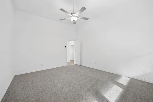 an empty room with a ceiling fan and a window